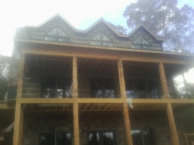Dormers and porch framing on a large log home under construction — Roof Coating work by our crew in Gibbon Glade