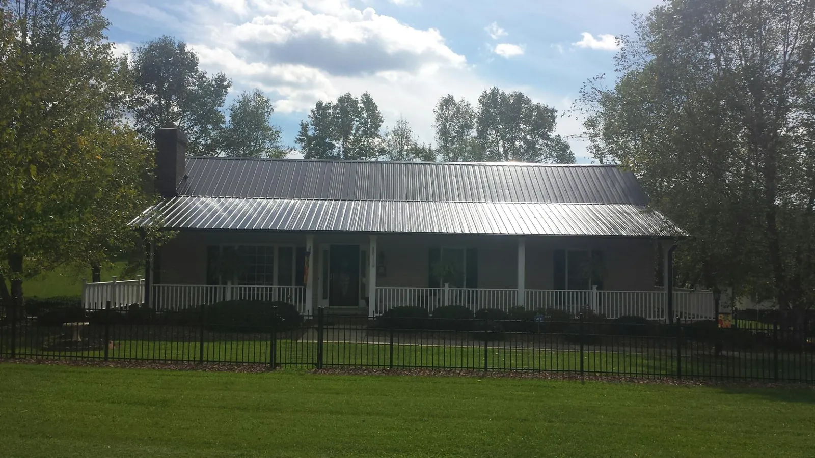 Gray metal roof on a brick ranch with a full width front porch — Gutter Guard Installation work by our crew in Gibbon Glade