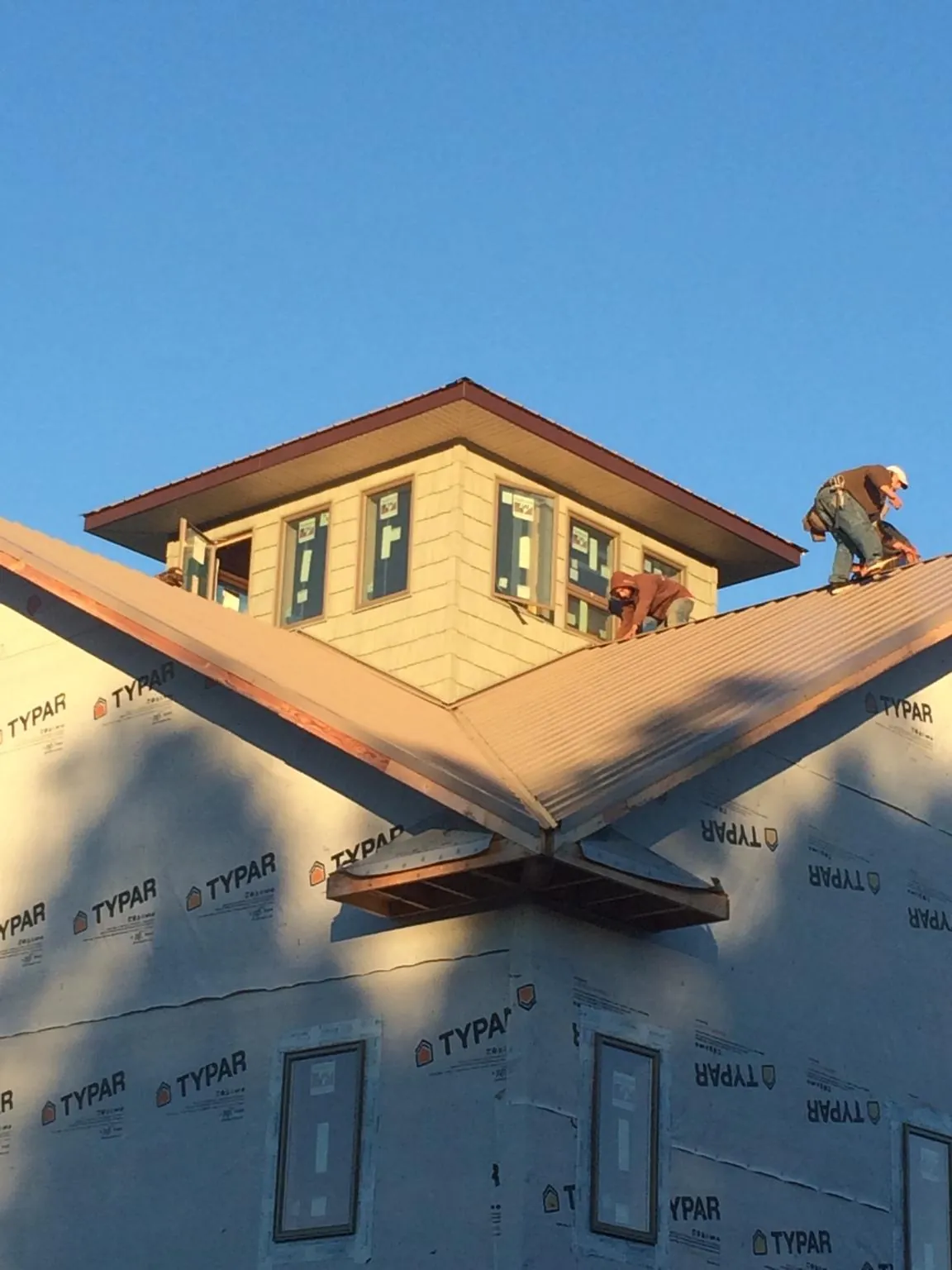Roofers working around a rooftop cupola on a new metal roof at sunset — Roof Waterproofing in Gibbon Glade by Roofing Brothers